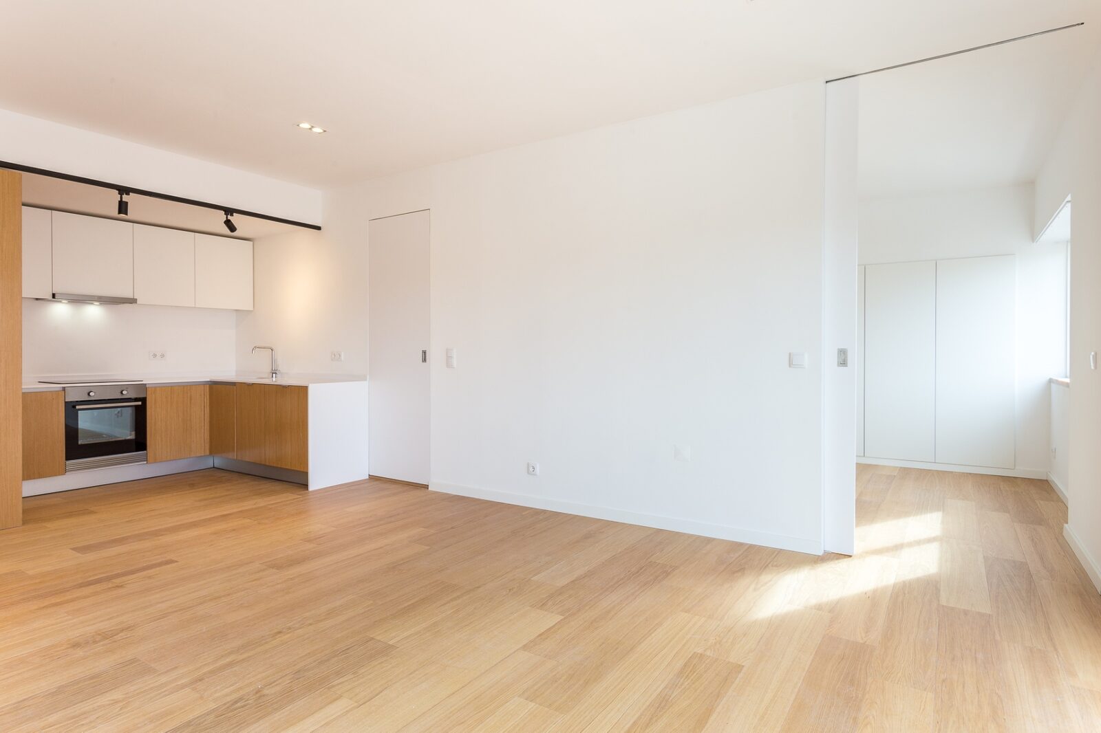 Sala aberta com cozinha em carvalho ao fundo e porta de correr — apartamento na Barceloneta, Barcelona