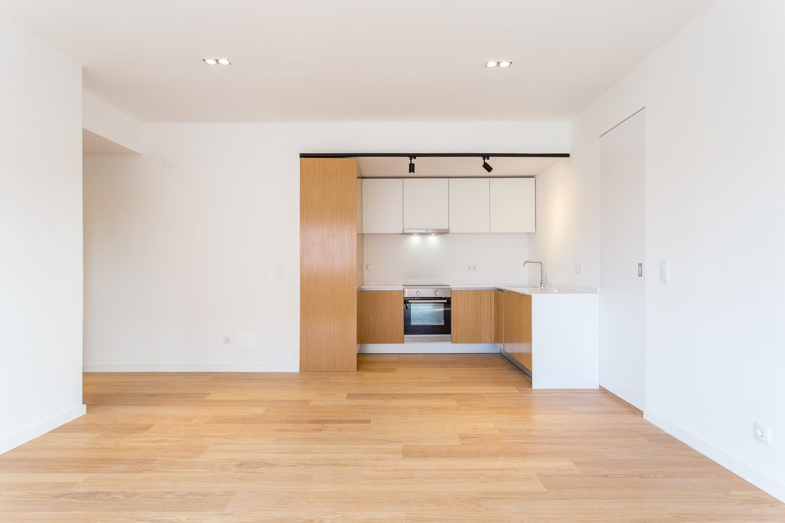 Living amplo com pavimento em carvalho claro e cozinha integrada — remodelação na Barceloneta