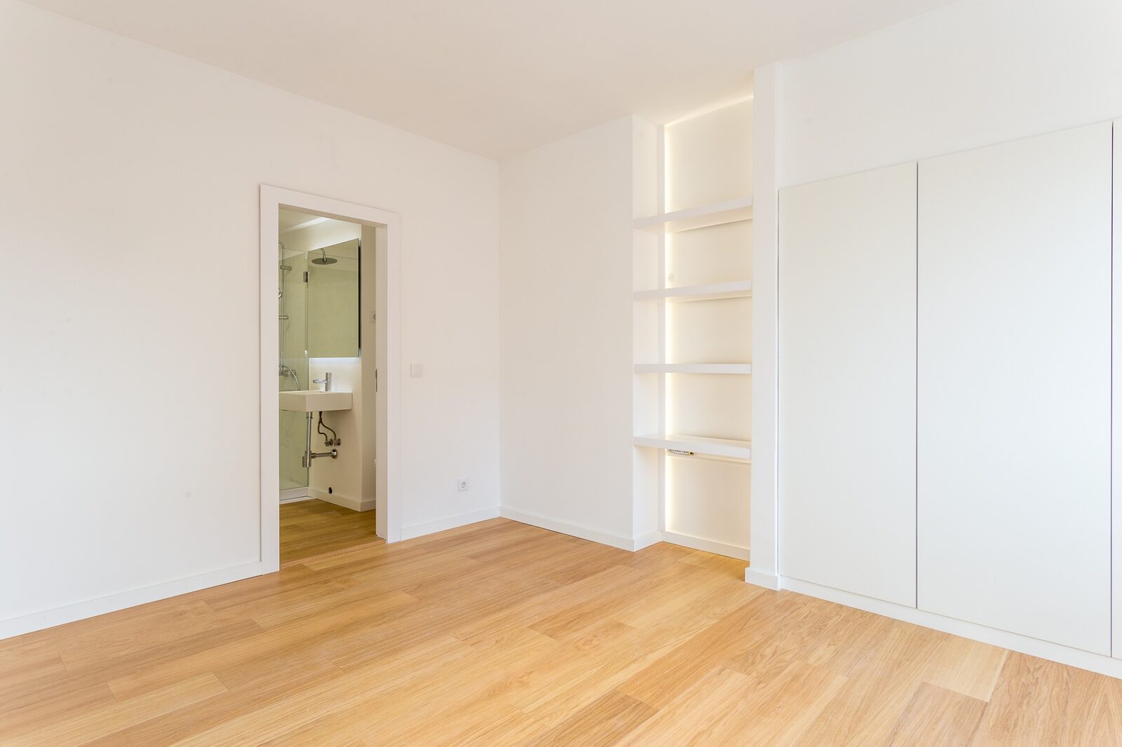 Quarto principal depois — paredes brancas, pavimento em carvalho, nicho iluminado e roupeiro embutido — Barceloneta