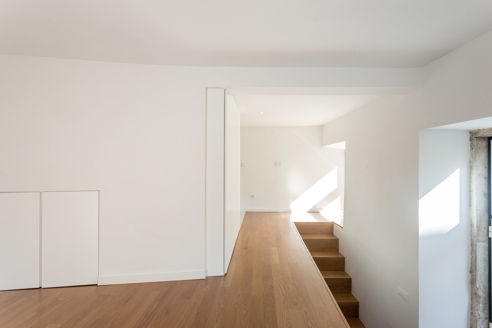 Mezanino superior com pavimento em madeira clara e vão para a sala — duplex em Lisboa
