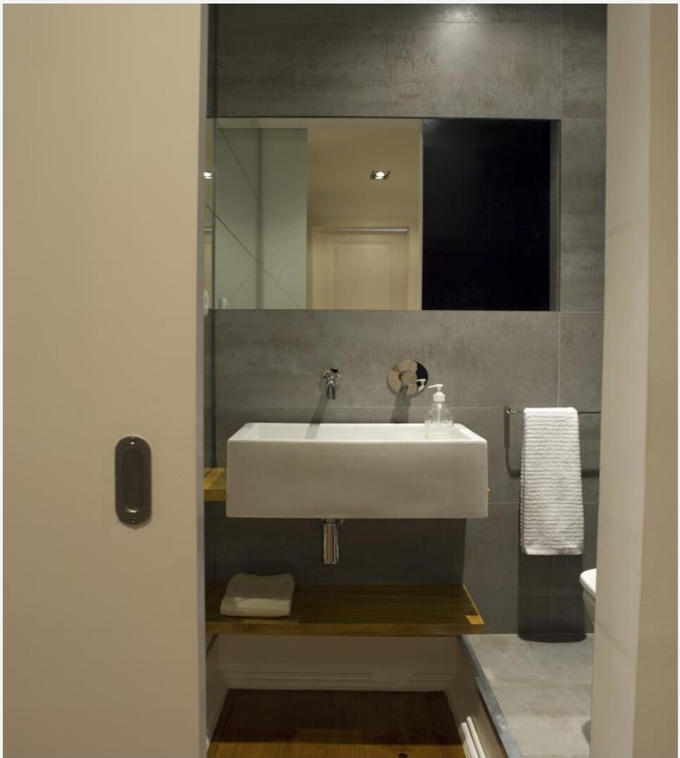 Casa-de-banho com lavatório branco, espelho e azulejos cinzentos, Saldanha
