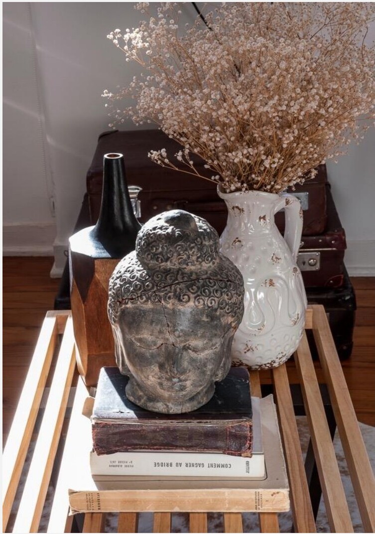 Detalhe decorativo — busto de Buda, vaso com flores secas e livros sobre banco de madeira, Avenida da Liberdade