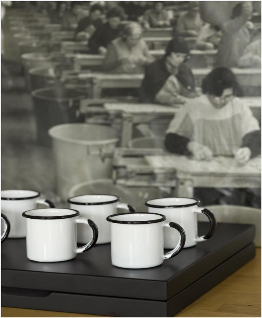 Detalhe de canecas brancas em esmalte sobre tabuleiro preto e fotografia a preto-e-branco ao fundo, Saldanha