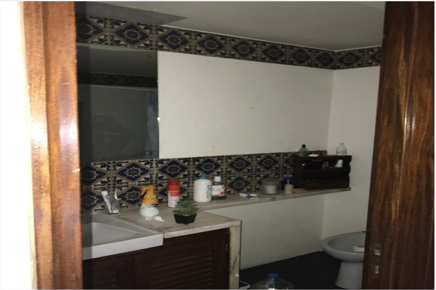 Casa-de-banho antiga com azulejos padronizados azuis e brancos, móvel em madeira escura e bidé — Barceloneta