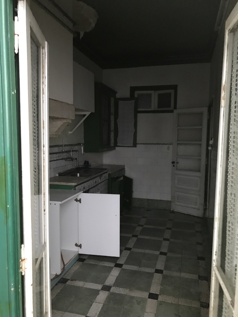 Cozinha antes — armários verdes e brancos, bancada antiga e pavimento em ladrilho hidráulico xadrez, Cabo Verde