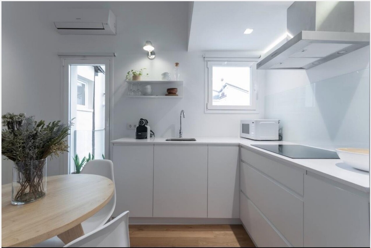Detalhe da cozinha branca minimalista com mesa redonda em carvalho — Madrid