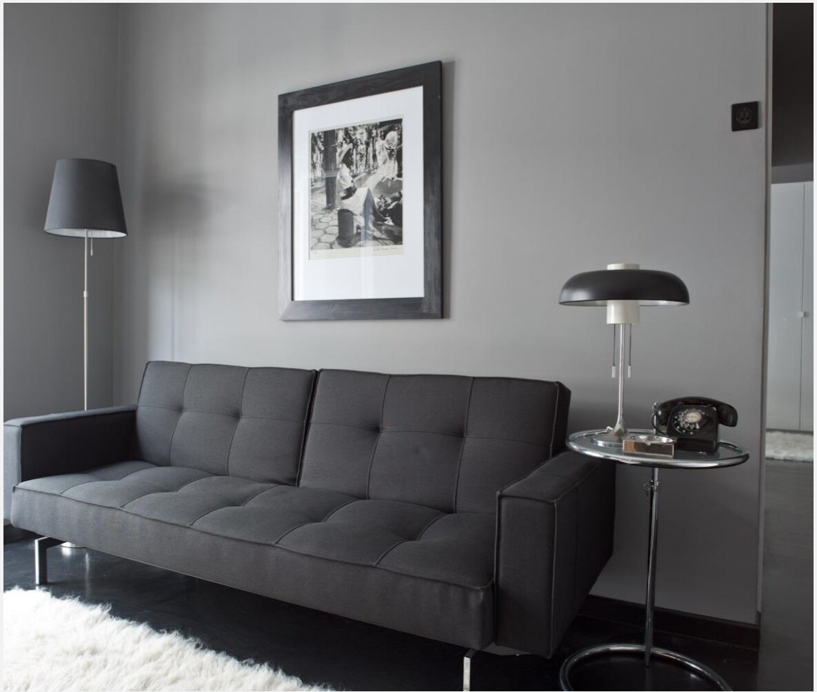 Sala decorada em escala de cinzas com sofá escultórico e candeeiro de mesa vintage — apartamento Marquês de Pombal, Lisboa · Palavra Decimal