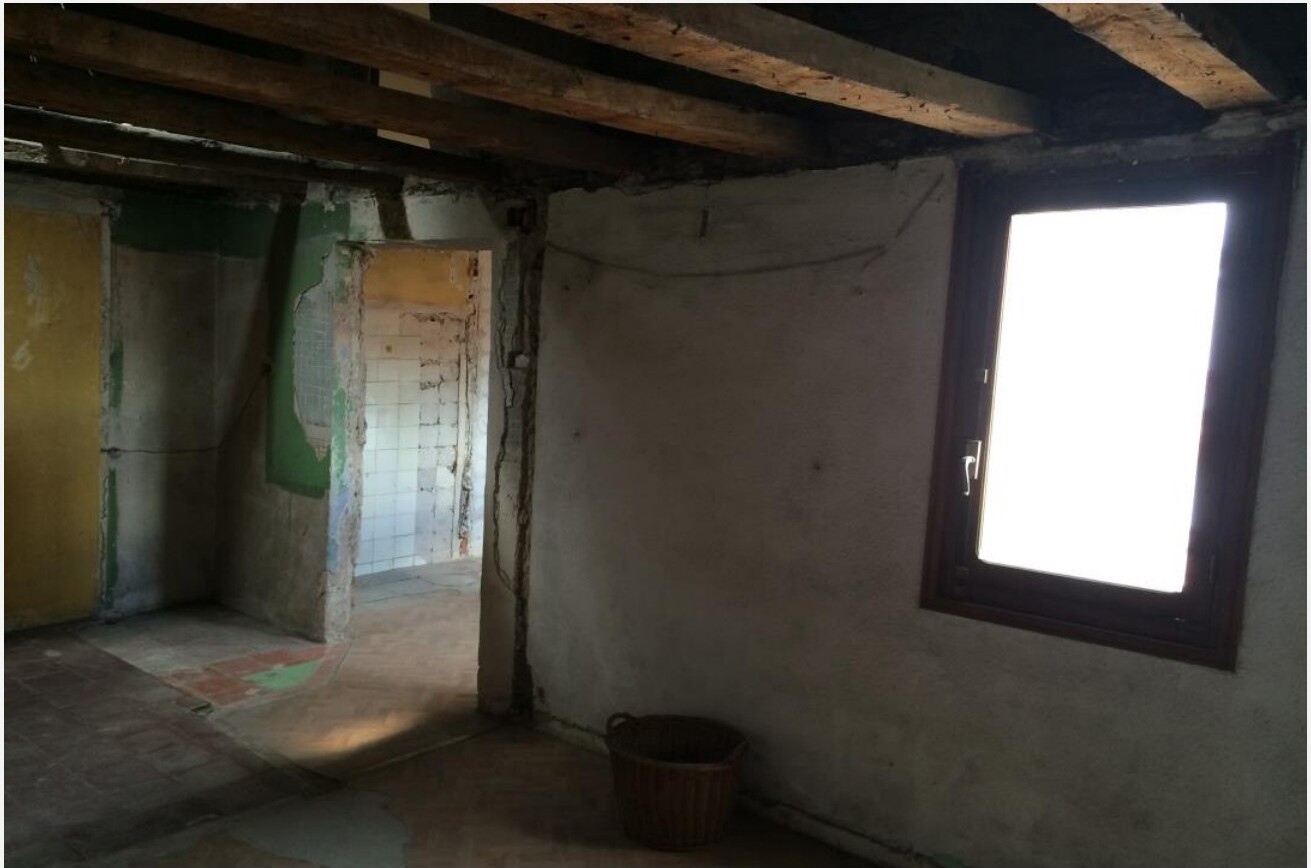 Sala antes da remodelação — vigas escuras, paredes em mau estado e janelas antigas, apartamento em Madrid