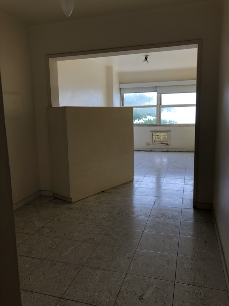 Sala antes — paredes amareladas, pavimento em ladrilho cerâmico antigo e meia-parede divisória — Copacabana, Rio de Janeiro