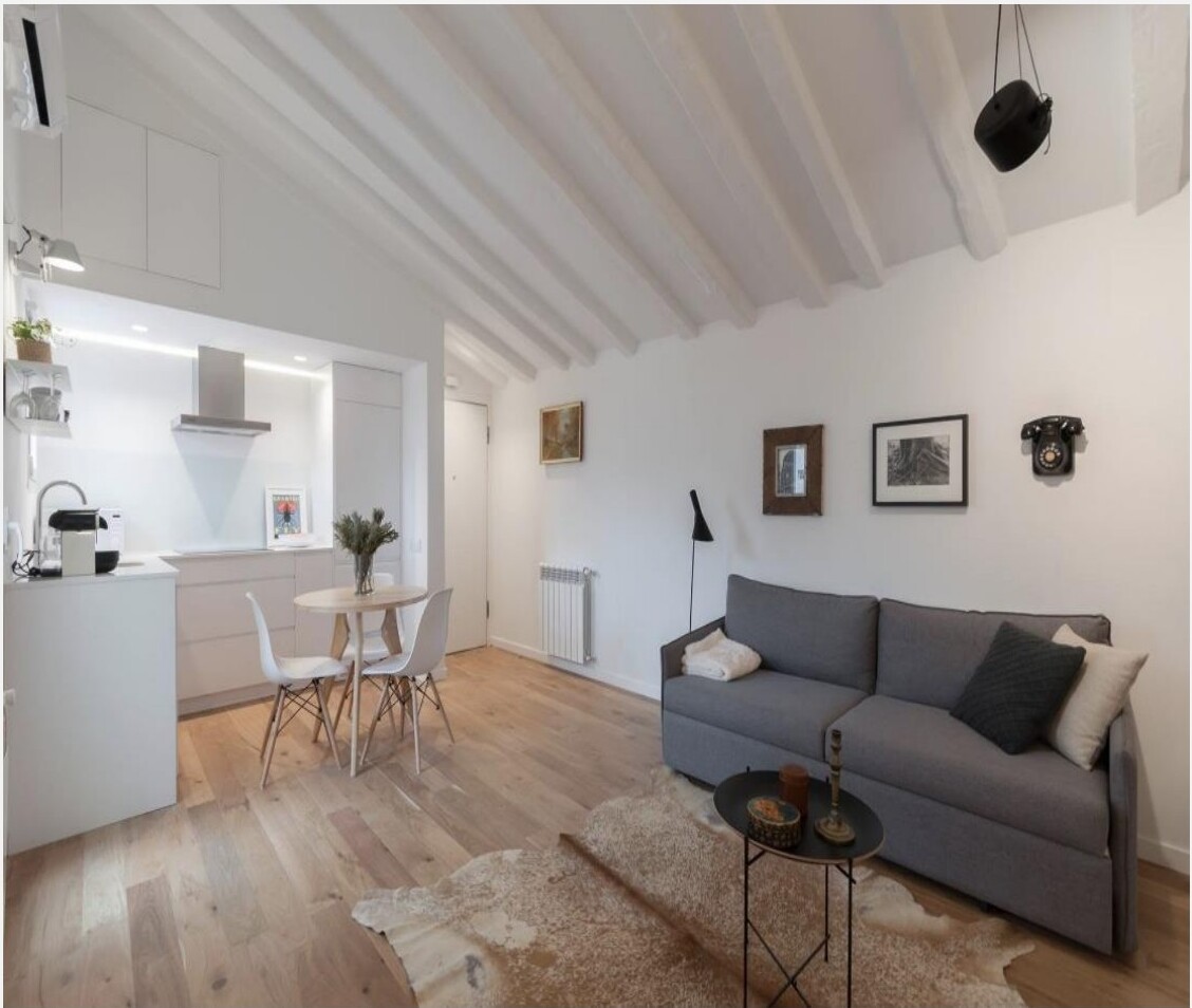 Apartamento duplex remodelado em Madrid com vigas de madeira recuperadas, escada para mezanino e sala em tons brancos — projecto Palavra Decimal