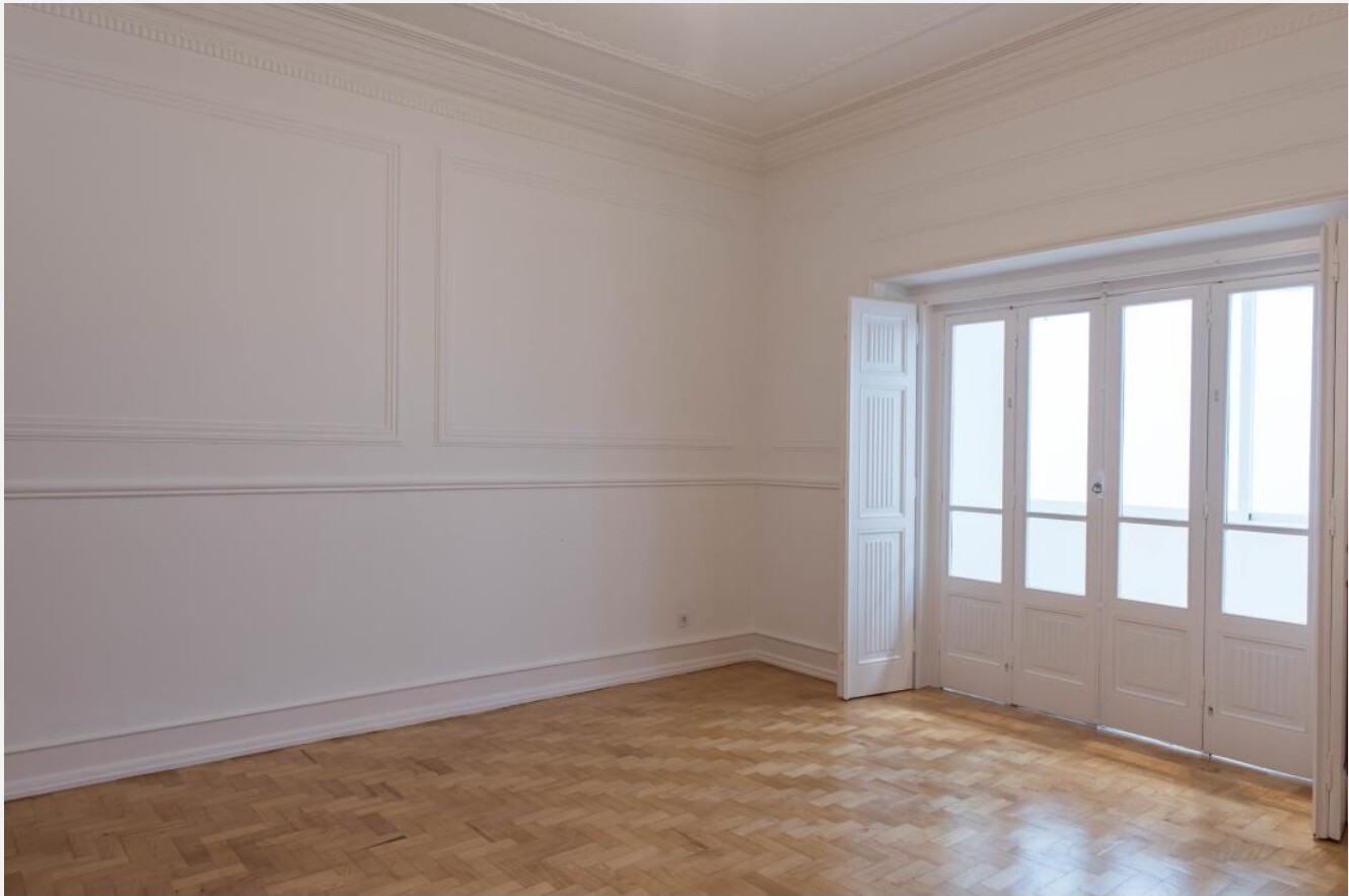Sala reabilitada de apartamento em Cabo Verde — paredes brancas, parquet e portas francesas · Palavra Decimal